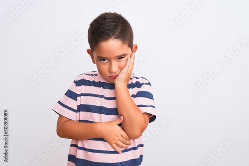 Beautiful kid boy wearing casual striped t-shirt standing over isolated white background thinking looking tired and bored with depression problems with crossed arms.