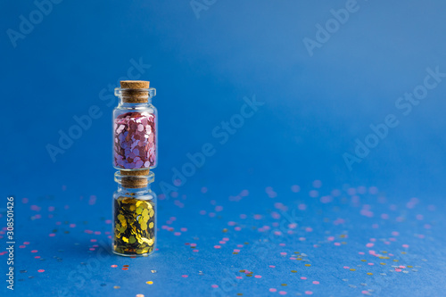 New Year and Christmas holiday blue background. Holidays,shopping and sales concept. Two small glass bottles with confetti