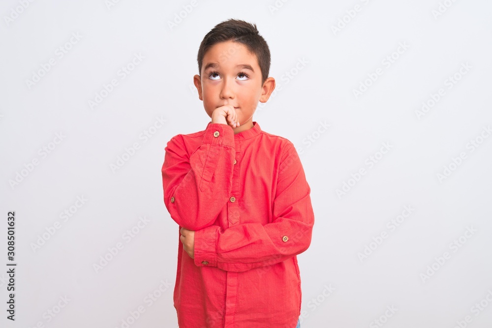 Beautiful kid boy wearing elegant red shirt standing over isolated white background with hand on chin thinking about question, pensive expression. Smiling with thoughtful face. Doubt concept. Beautiful kid boy wearing elegant red shirt standing over isolated white background with hand on chin thinking about question, pensive expression. Smiling with thoughtful face. Doubt concept.
