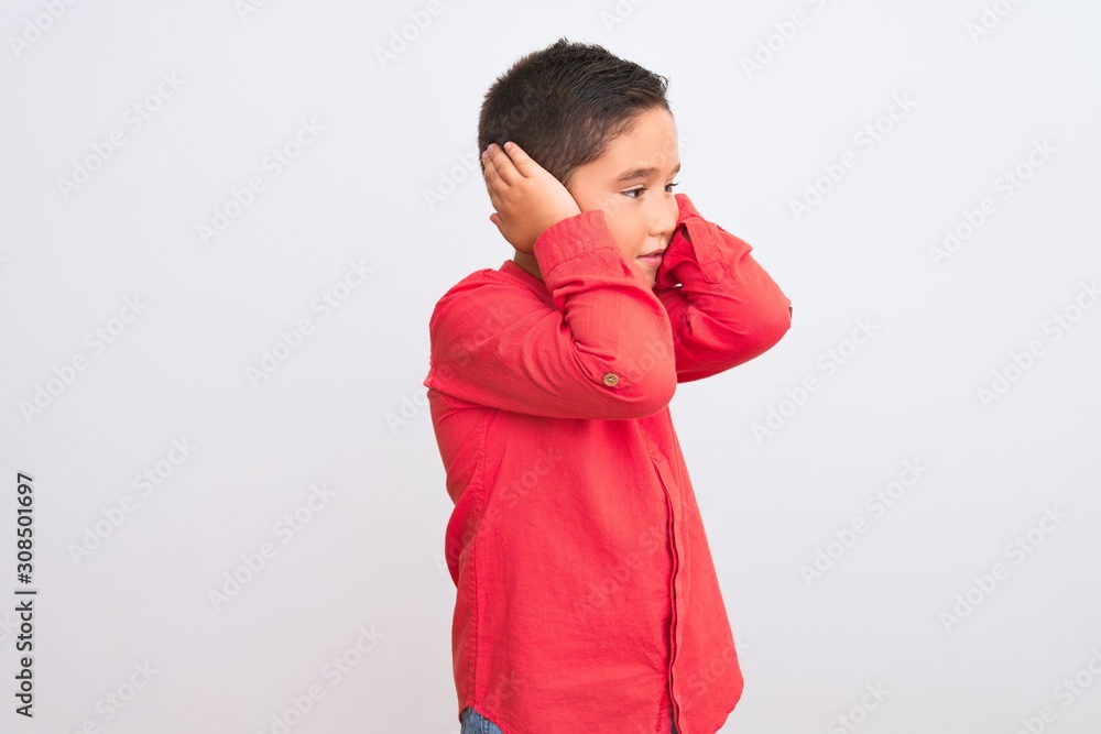 Beautiful kid boy wearing elegant red shirt standing over isolated white background with hand on head for pain in head because stress. Suffering migraine. Beautiful kid boy wearing elegant red shirt standing over isolated white background with hand on head for pain in head because stress. Suffering migraine.