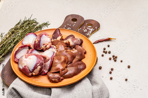 Fresh raw duck offal: heart, liver, stomach. Dry spices, salt, chili pepper. Wooden cutting boards, stone concrete background photo