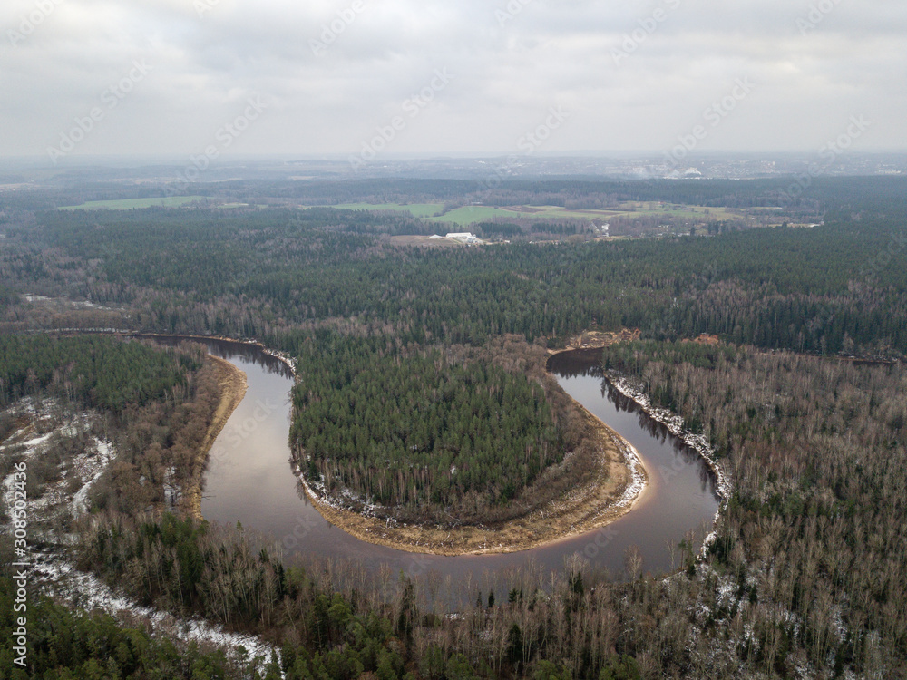 River in winter forest with green trees from above. Aerial drone image of river Gauja in Latvia River in winter forest with green trees from above. Aerial drone image of river Gauja in Latvia