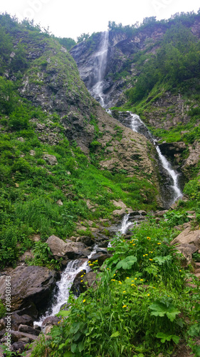 Scenic landscape with beautiful waterfall in forest among rich vegetation. spring water flows from mountainside.