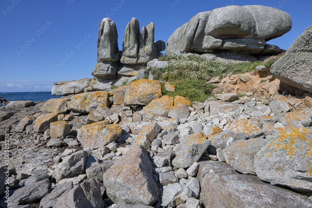 Big rocks with grass and moss at the coast of Brittany, blue sky