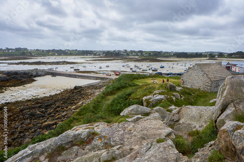 Coastal region of Brittany with houses  grass and rocks  low tide with small boats on the sand