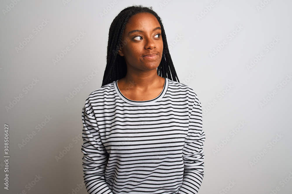 Young african american woman wearing striped t-shirt standing over isolated white background smiling looking to the side and staring away thinking. Young african american woman wearing striped t-shirt standing over isolated white background smiling looking to the side and staring away thinking.