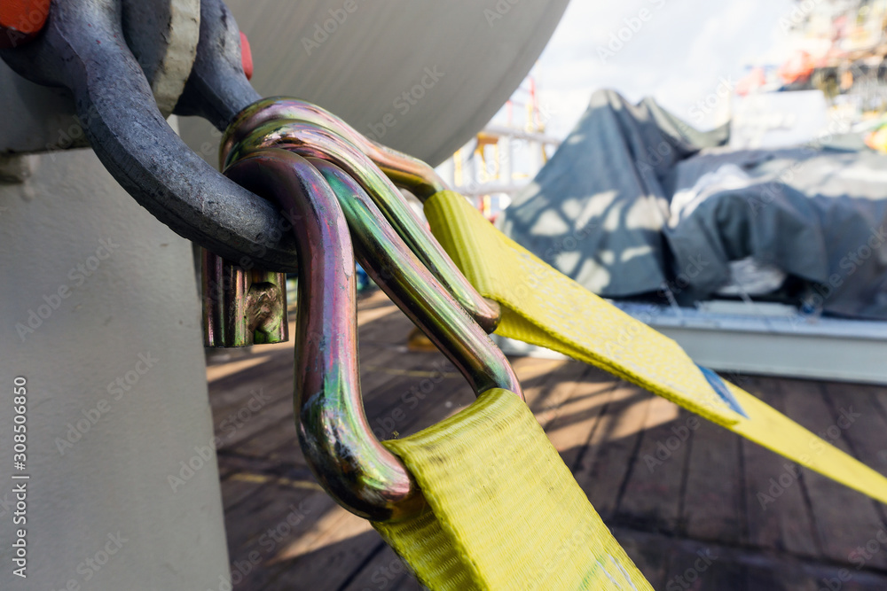 Cargo strap hook secured to ashckle for tiedown of a vessel on deck of