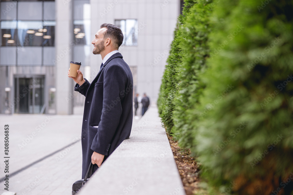 Delighted bearded male standing near business center Delighted bearded male standing near business center