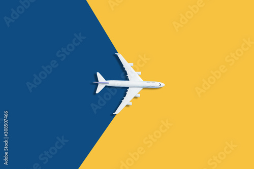 Flat lay design of travel concept with plane on blue and yellow background with copy space