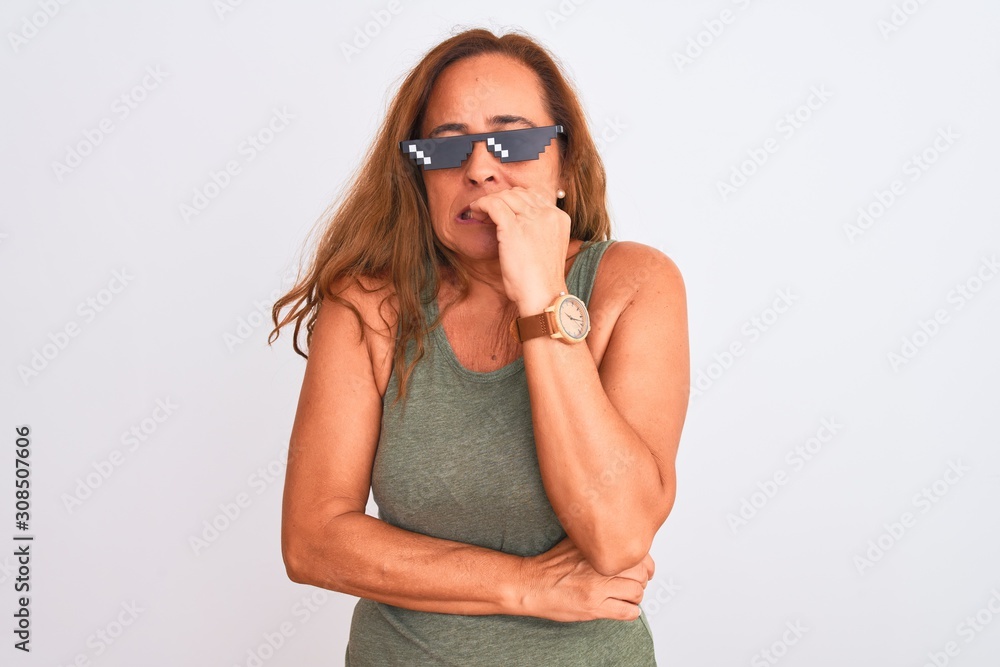 Middle age mature woman wearing thug life sunglasses over isolated background looking stressed and nervous with hands on mouth biting nails. Anxiety problem. Middle age mature woman wearing thug life sunglasses over isolated background looking stressed and nervous with hands on mouth biting nails. Anxiety problem.