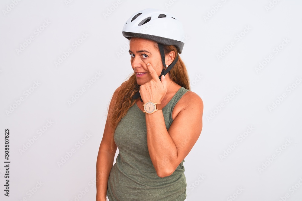 Middle age mature cyclist woman wearing safety helmet over isolated background Pointing to the eye watching you gesture, suspicious expression Middle age mature cyclist woman wearing safety helmet over isolated background Pointing to the eye watching you gesture, suspicious expression