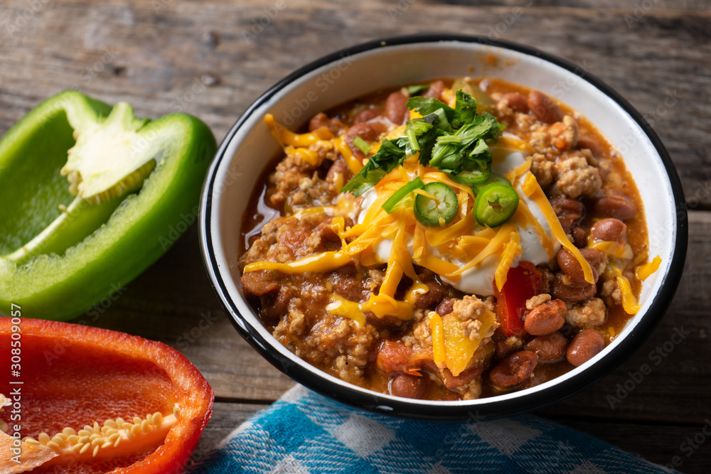Texmex dish called "Chili con carne" with cheese and sour cream on wooden background - obrazy, fototapety, plakaty 