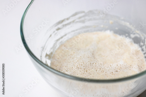 raw sour dough whole wheat pastry for bread, prosess of mixing pre-dough in glass bowl, knead, horizontal with copy space, selectuve focus, healthy food, nutritious. White background