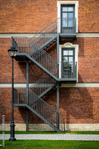 Black wrought iron staircase on red brick wall