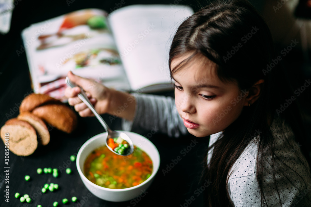 Little girl eating vegetable soup at the table Little girl eating vegetable soup at the table