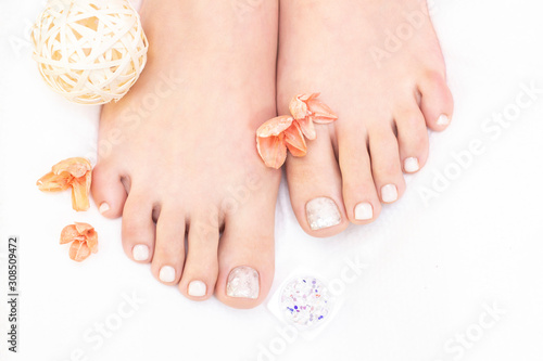 Female legs on a white background. Nails get a fresh and neat look during the pedicure procedure. Close up of female legs in spa salon.