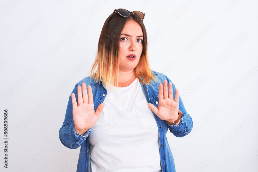 Beautiful woman wearing denim shirt standing over isolated white background Moving away hands palms showing refusal and denial with afraid and disgusting expression. Stop and forbidden. Beautiful woman wearing denim shirt standing over isolated white background Moving away hands palms showing refusal and denial with afraid and disgusting expression. Stop and forbidden.