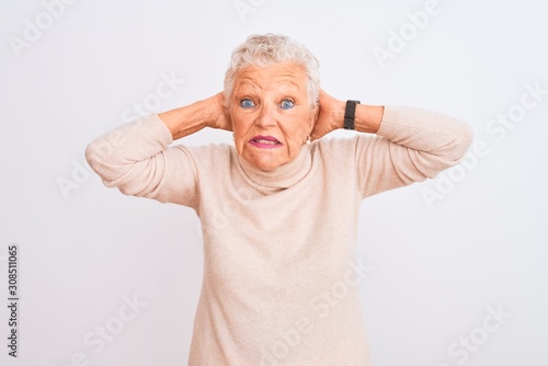 Senior grey-haired woman wearing turtleneck sweater standing over isolated white background Crazy and scared with hands on head, afraid and surprised of shock with open mouth