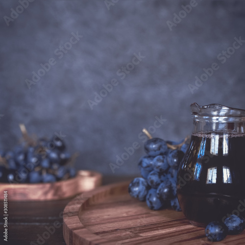 grape juice in a glass transparent jug and clusters of ripe grapes close-up. background with grape juice and grapes.