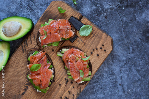 Sandwich with avocado and salmon on a concrete background. View from above.