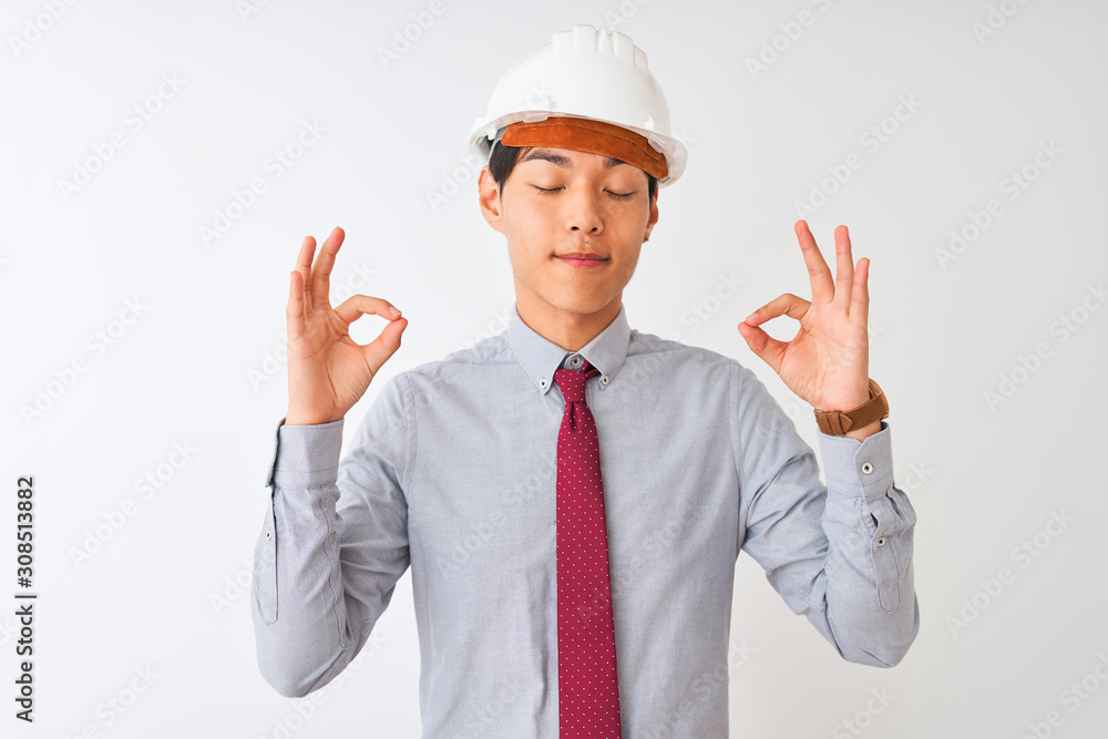 Chinese architect man wearing tie and helmet standing over isolated white background relax and smiling with eyes closed doing meditation gesture with fingers. Yoga concept. Chinese architect man wearing tie and helmet standing over isolated white background relax and smiling with eyes closed doing meditation gesture with fingers. Yoga concept.