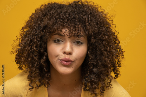 African american woman with afro hairstyle and glamour glam makeup. Yellow background.
