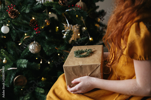Tableau sur toile Red-haired girl holding a Christmas gift on her lap