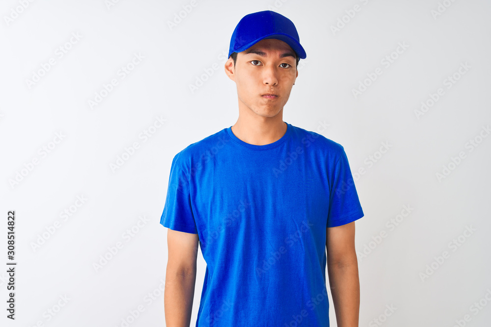 Chinese deliveryman wearing blue t-shirt and cap standing over isolated white background depressed and worry for distress, crying angry and afraid. Sad expression.