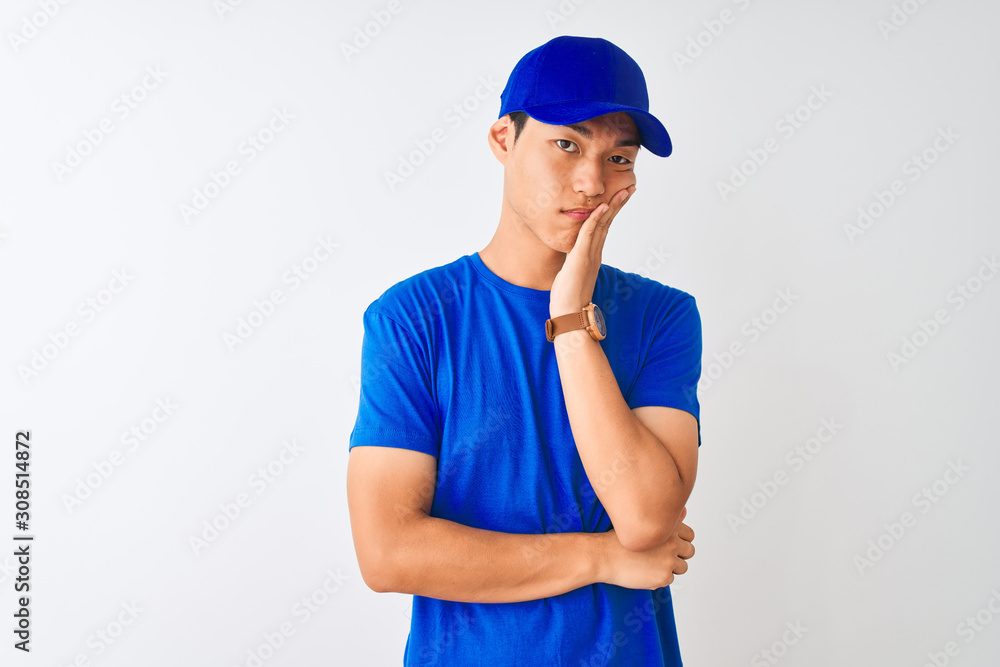 Chinese deliveryman wearing blue t-shirt and cap standing over isolated white background thinking looking tired and bored with depression problems with crossed arms. Chinese deliveryman wearing blue t-shirt and cap standing over isolated white background thinking looking tired and bored with depression problems with crossed arms.