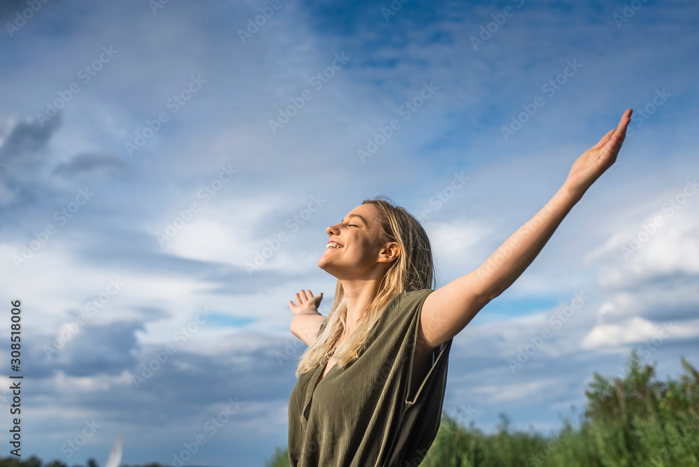 Smiling woman standing with outstretched arms outdoors Smiling woman standing with outstretched arms outdoors