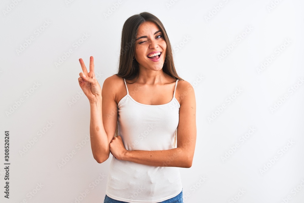 Young beautiful woman wearing casual t-shirt standing over isolated white background smiling with happy face winking at the camera doing victory sign. Number two. Young beautiful woman wearing casual t-shirt standing over isolated white background smiling with happy face winking at the camera doing victory sign. Number two.