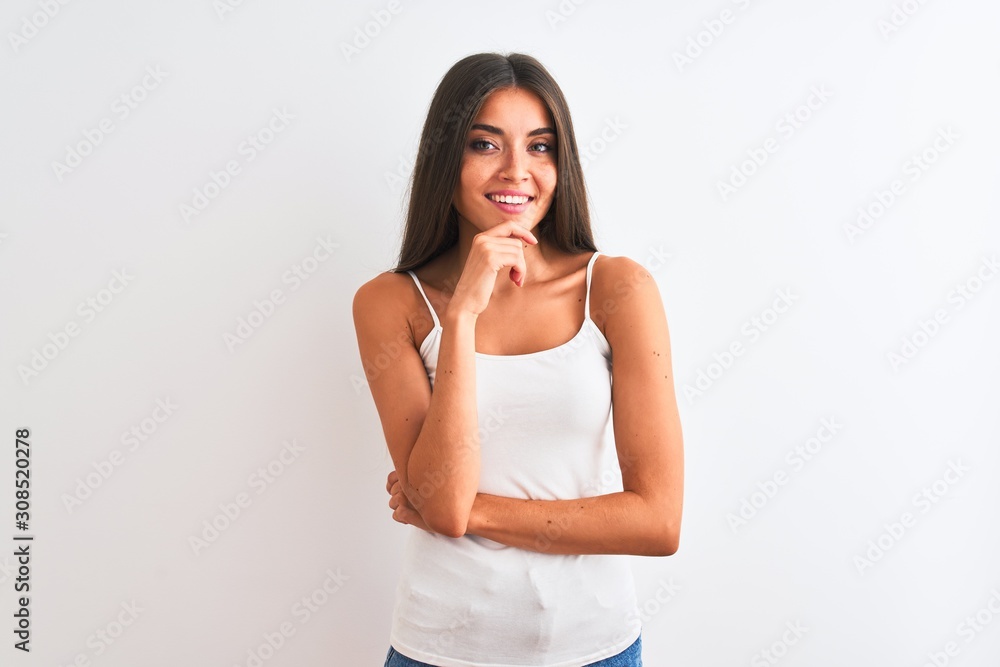 Young beautiful woman wearing casual t-shirt standing over isolated white background looking confident at the camera smiling with crossed arms and hand raised on chin. Thinking positive. Young beautiful woman wearing casual t-shirt standing over isolated white background looking confident at the camera smiling with crossed arms and hand raised on chin. Thinking positive.