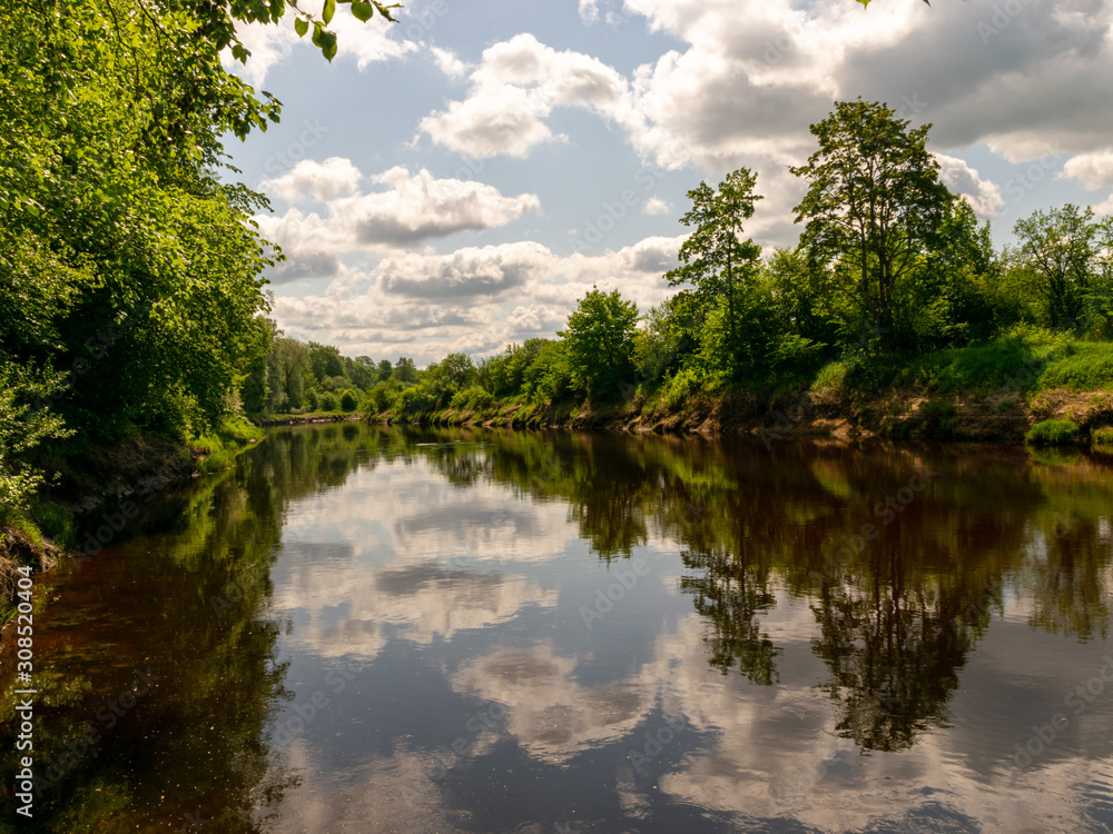summer landscape with river, green trees on shore and clouds, beautiful glare summer landscape with river, green trees on shore and clouds, beautiful glare