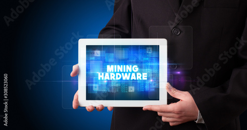 Wallpaper Mural Young business person working on tablet and shows the inscription: MINING HARDWARE Torontodigital.ca