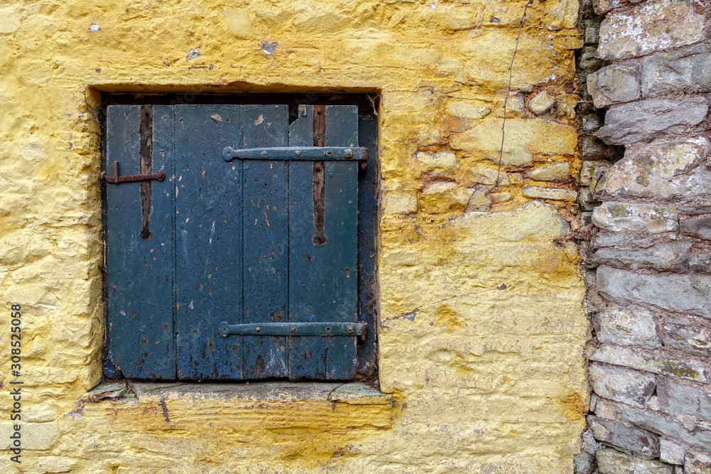 old blu wooden window in a yellow stone wall old blu wooden window in a yellow stone wall