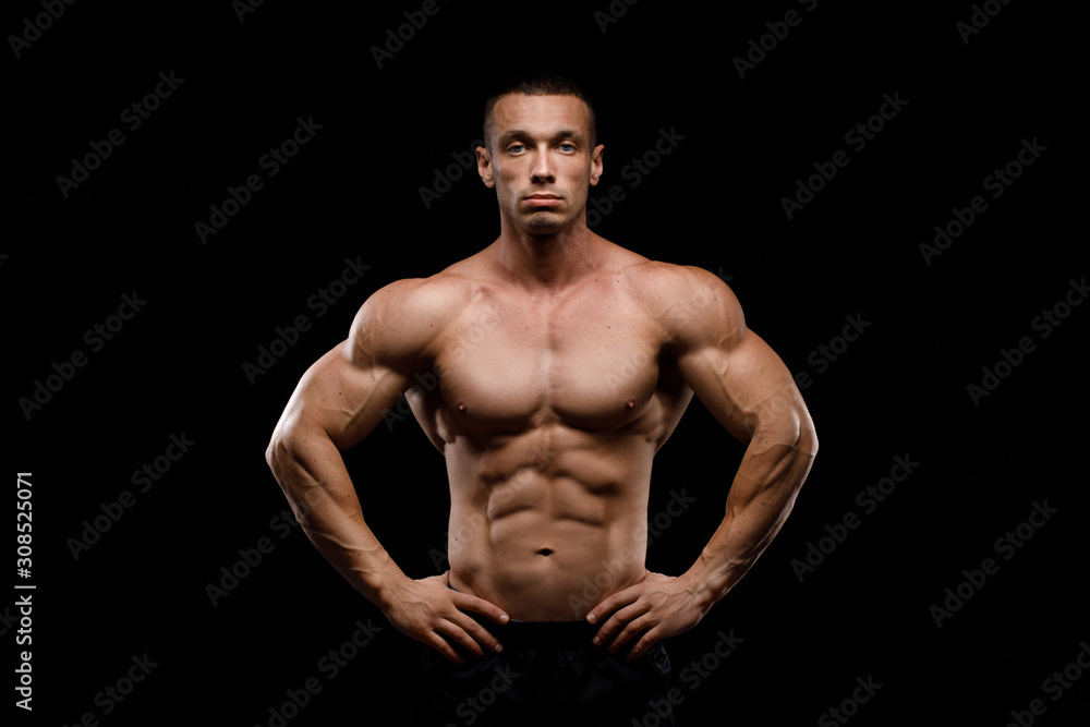 Fototapeta premium Sexy torso. Muscular model sports young man in jeans showing his press on a black background. Fashion portrait of sporty healthy strong muscle guy. 