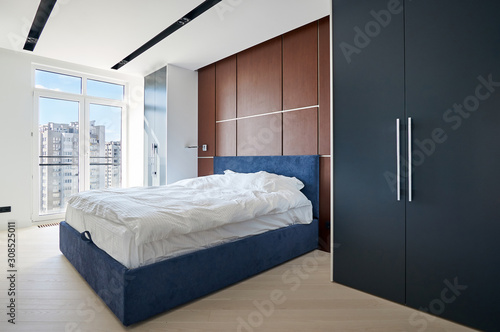 Obraz na plátně Modern bedroom with fitted wardrobes, a double bed with a cushioned headboard an