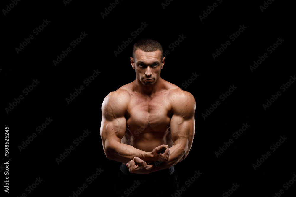Sexy torso. Muscular model sports young man in jeans showing his press on a black background. Fashion portrait of sporty healthy strong muscle guy. 
