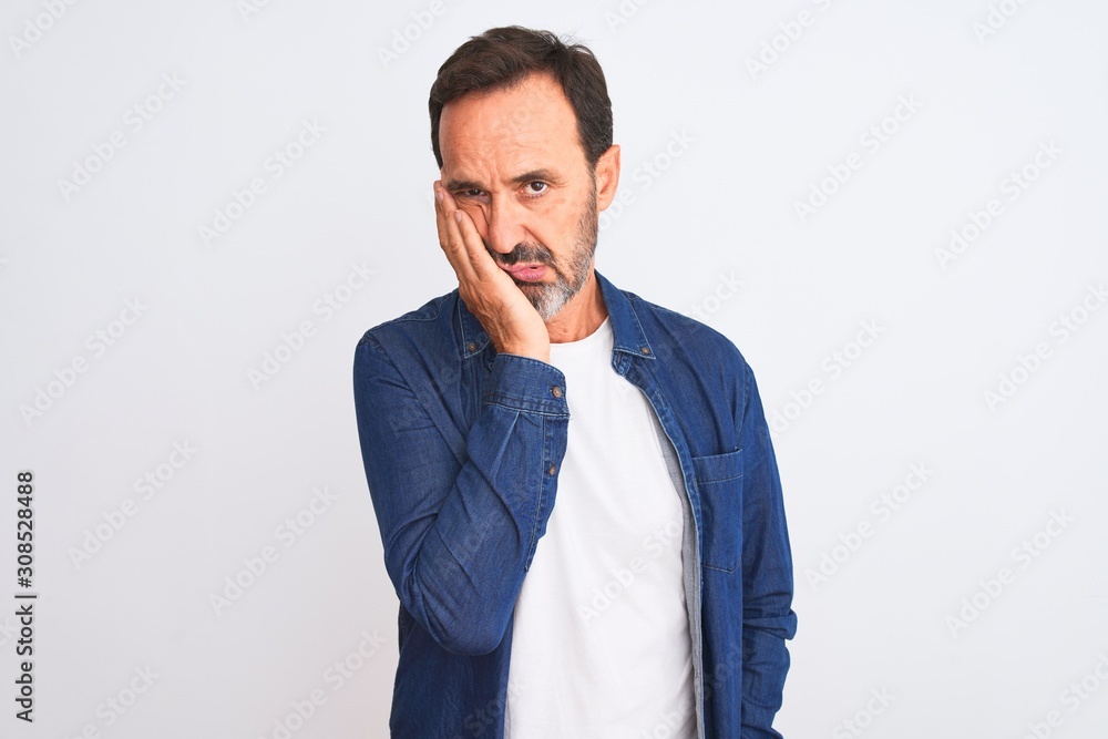 Middle age handsome man wearing blue denim shirt standing over isolated white background thinking looking tired and bored with depression problems with crossed arms. Middle age handsome man wearing blue denim shirt standing over isolated white background thinking looking tired and bored with depression problems with crossed arms.