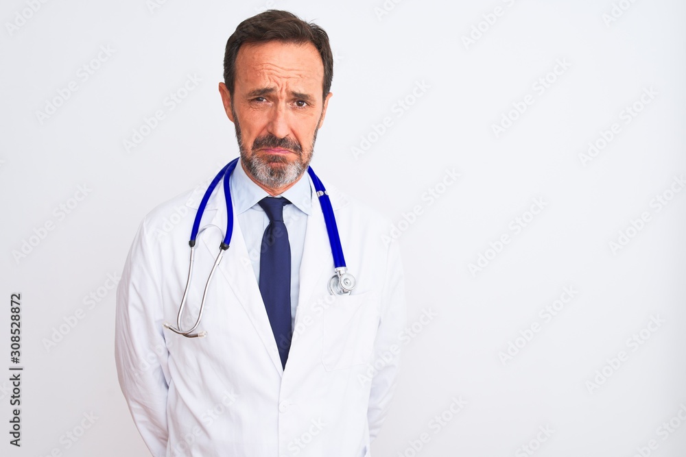 Middle age doctor man wearing coat and stethoscope standing over isolated white background depressed and worry for distress, crying angry and afraid. Sad expression.