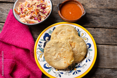 Salvadoran pupusas with coleslaw and tomato sauce on wooden background