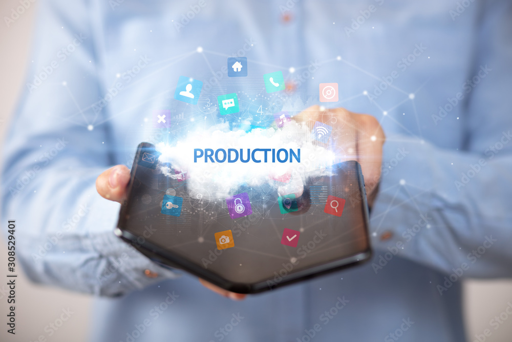 Businessman holding a foldable smartphone with PRODUCTION inscription, technology concept Businessman holding a foldable smartphone with PRODUCTION inscription, technology concept