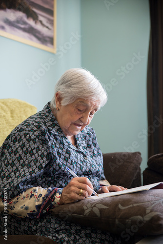 Senior woman doing crossword puzzle at home photo