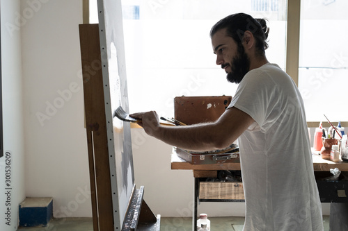 young painter working with big brush on a white canvas that we have pu photo