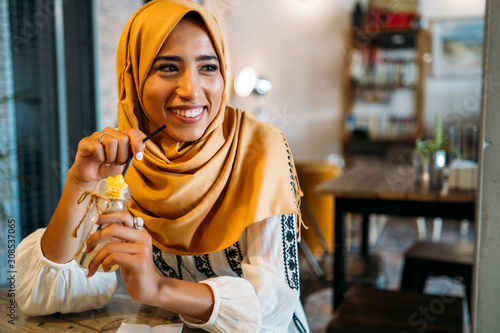 Young muslim woman wearing yellow hijab in a cafe photo