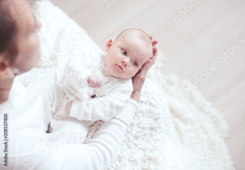 Cute baby 1 year old ying on mother hands in room closeup. Motherhood. Maternity. Childhood.