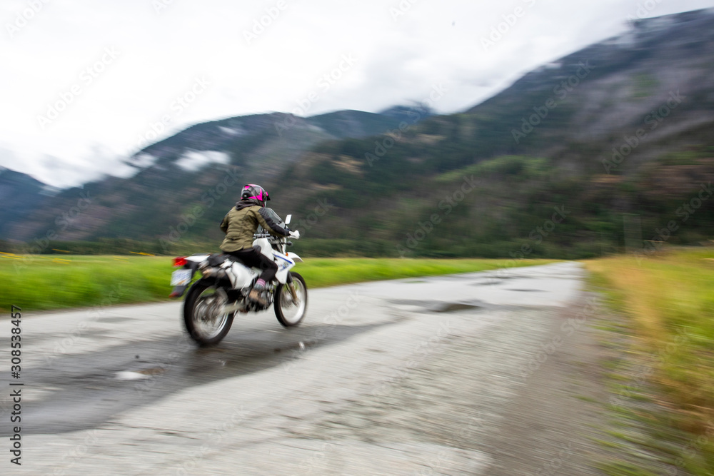 A woman rides her motorcycle on a cloudy summer day. A woman rides her motorcycle on a cloudy summer day.