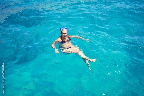 Young woman wearing diving googles swimming and doing snorket at the sea
