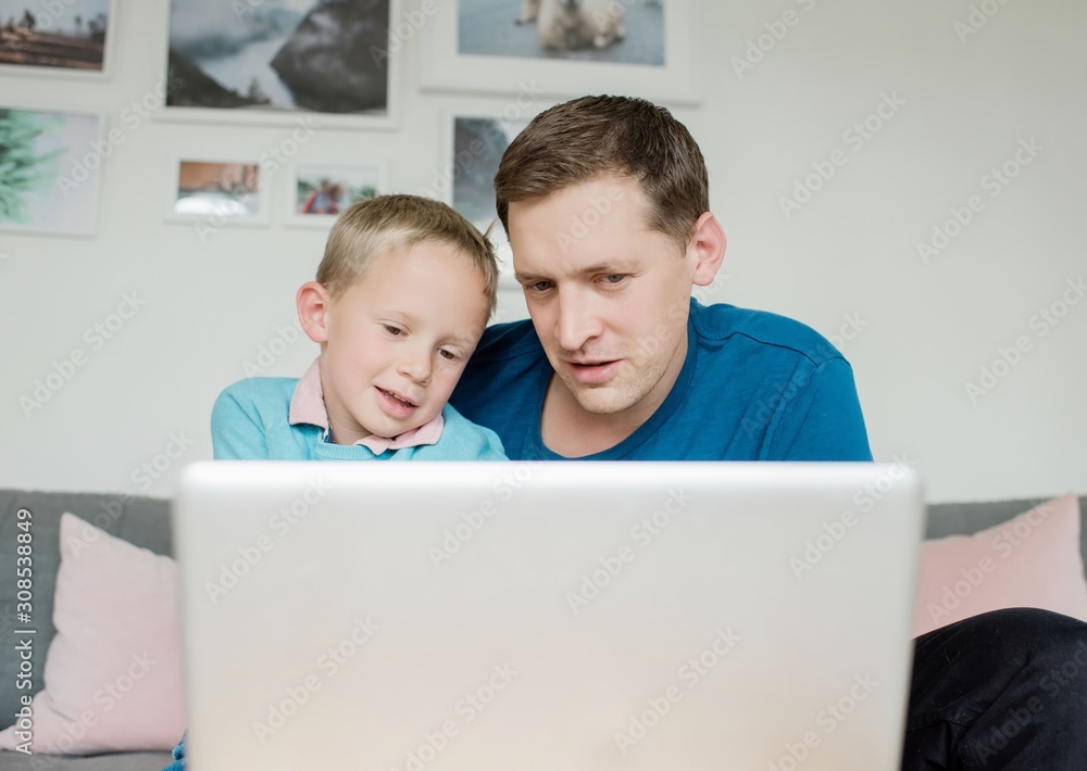 father and soon smiling looking at a laptop at home together father and soon smiling looking at a laptop at home together