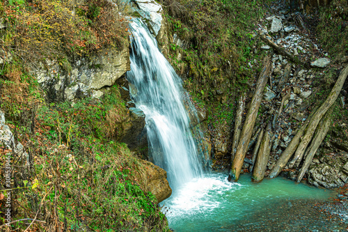 Scenic waterfall flows through the forest in the mountains.